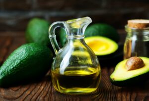 aceite de aguacate sobre una mesa con frutos de aguacate alrededor